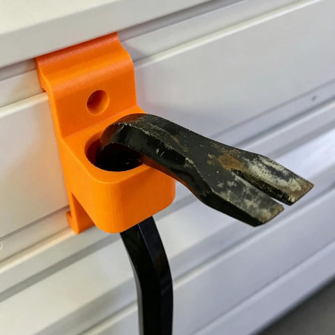 Heavy Duty Garage Hooks That Fit Track Panels holding a black tool on orange metal hanger mounted on a wall.