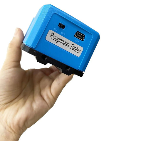 Top Shelf Surface Roughness Tester With Slim Needle For Tricky Grooves And Curved Surfaces Heavy Duty Metal Stand Plug And Play Pc Link Crisp Oled Panel Twenty Parameters Dead On Accuracy, blue portable unit in hand.