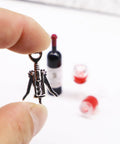 Hella Cool Miniature Red Wine Bottle Set Featuring Two Resin Filled Wine Glasses And A Static Corkscrew displayed in hand.