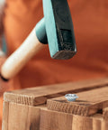 Close-up of a 3/8-16 zinc-plated steel T-nut on wood with hammer overhead.