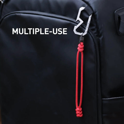 Badass Titanium Keychain Carabiner Multitool With Bottle Opener on backpack strap, featuring red paracord loop.