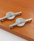 Two metal slider wheels on wood surface, part of 8 Pack Rock Hard Nylon Slider Wheel Replacement Pulleys for Walk in Closets Cabinet and Chiller Doors Smooth Rolling Track Upgrade with Easy Peasy Snap Fit Design Durable Abs Build for Hotel and Restaurant Fixups.