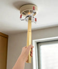 Skip The Ladder Drama With This Sturdy Aluminum Alloy Smoke Detector Remover Tool reaching for a ceiling fire sensor.