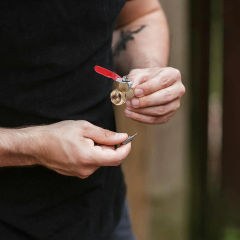 Person holding a Heavy Duty Copper Ball Valve 6 Pack Built Tough NPT Thread connector with red handle for easy shut off.