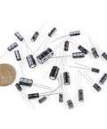 Killer Value Aluminum Electrolytic Capacitor Assortment Kit Featuring 24 Distinct Options Across 10V 16V 25V And 50V Voltages Spanning 0.1UF To 1000UF with coins for size reference.