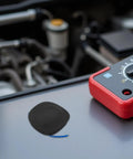Automatic Fire Suppression System And Vehicle Fire Extinguisher With Self Activating Aerosol Mechanism For Cars Trucks And Vans, compact black sensor on metal surface.