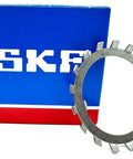 Pro Grade W11 Lock Washer For Bearings with 2.18 Inch Inner Diameter resting beside blue SKF box, showcasing heavy-duty design.