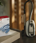 Box of HyClean GN Vacuum Bags Compatible With Complete C2 C3 S8 S5 S2 Canisters on a table next to a vacuum cleaner