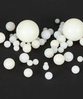 20 Pack White Nylon Bearing Balls Three Quarter Inch G2 precision spheres scattered on black background, showing different sizes.