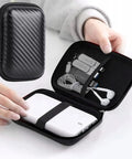 Rugged EVA External Hard Drive Case Pouch For SSDs And HDDs, shown open with tech accessories inside, shockproof black, 11.5 x 7.5 x 3.5 cm.