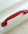 Hella Durable Zinc Alloy Drawer Knobs And Kitchen Cabinet Handles Built Tough For Daily Use Featuring Easy Grip Pulls For Dressers And Kids Furniture Hardware In Totally Dope Colors. Red zinc alloy handle on textured white cabinet.