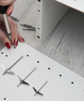 Person installing Seriously Tough Drywall Toggle Bolts And Wing Nuts Kit 24 Pieces Galvanized Iron Set, wood background.