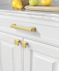 Premium Brushed Gold Drawer Pulls 10 Pack 5 Inch Cabinet Handles on white cabinets with fruit on countertop.