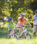 Family biking through park trail, wearing helmets and casual clothes on sunny day