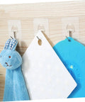 Super Tough Clear Adhesive Wall Hooks 12 Pack Stainless Steel holding a blue bunny plush and hanging items on a wood surface.