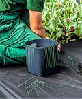 Person using Heavy Duty Garden Stakes And Ground Anchors U Shape Steel Nails for artificial grass, sod, and weed fabric installation.