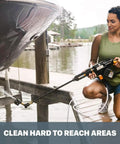 Woman using Deluxe Accessory Kit For Hydroshot Power Washers cleaning under boat with brush and soap dispenser on dock.