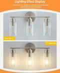 Three Light Bathroom Vanity Light Fixture In Brushed Nickel With Clear Glass Shades Over Mirror Wall Sconce On and Off Lighting Display