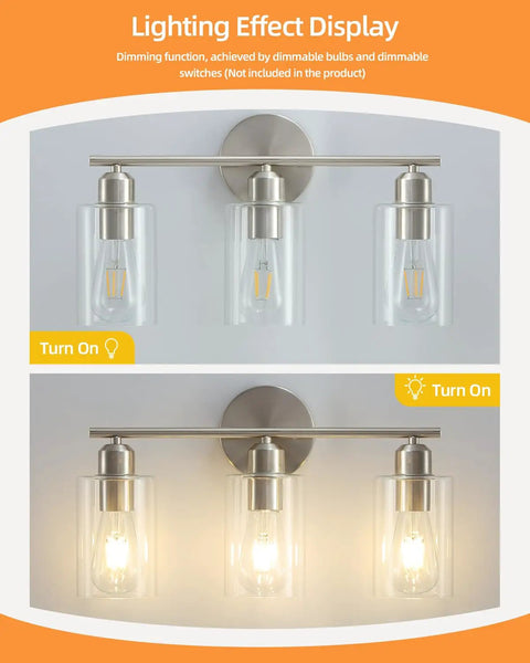 Three Light Bathroom Vanity Light Fixture In Brushed Nickel With Clear Glass Shades Over Mirror Wall Sconce On and Off Lighting Display