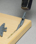 Gray snap connector from Kickass Wood Jointing Kit being hammered into wood for secure joint installation.