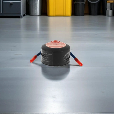 No Brainer Car Safety Upgrade Automatic Aerosol Fire Extinguisher With Rapid Heat Activation and Peel Stick Adhesive Mount for Engine Bays Garages and Office Spaces on a garage floor.