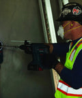 Worker using Dust Collection Attachment For SDS Max Hammer Drill With Dual Air Chambers And Wall Suction, drilling into wall.