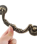 Close-up of decorative 5 Piece Drop Bail Cabinet Handle in bronze finish, showing intricate design and durable construction.