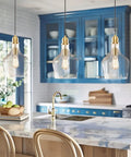 Hand Blown Glass Bell Pendant Light in Gold and Clear, Industrial Farmhouse Style, 9 Inch Shade over a kitchen island.