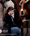 Person adjusting horse saddle wearing Ultimate Hands Free Headlamp Blasting Six Hundred Lumens Up To One Hundred Fifty Meters Away Great For Work Hard Hats And Nighttime Adventures With Red Rear Safety Light And Advanced Focus System Lightweight At One Hundred Fifty Eight Grams