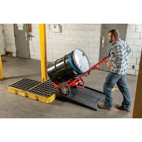 Worker using drum modular spill platform for customizable spill control, heavy duty build, 26.25 x 26 x 6.5 inches, 15 gallon sump, 2000 lb load capacity containment tray, made in USA, yellow, 1633 in a warehouse setting.