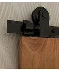 Close-up of Extra Heavy Duty Industrial Barn Door Hardware Kit 15 FT Rail System with black roller and wood door.