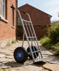 Four Pack 8 X 1.75 Inch Solid Rubber Wheels Featuring Flat Free Design mounted on a heavy-duty hand truck outdoors.