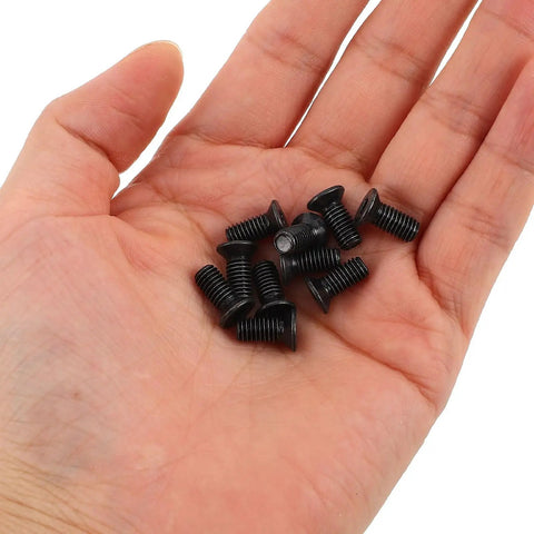 Hand holding small black screws from Electric Scooter Front Shock Absorber Replacement Screws Kit With Allen Wrench Stainless Steel Flat Head Hex Socket Hardware For Quick No Fuss Maintenance And Easy Install