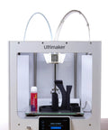 Essential All In One 3D Printer Adhesive Glue Delivering Bulletproof Hold For PLA ABS PETG TPU And Hips 50 Ml Bottle next to 3D printer with black print