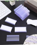 Heavy Duty PVC Wire Shelf Label Holders 30 Pack Clear Display Fronts on a desk with price tag cards and keyboard.