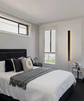 Modern No Fuss Plug In Long Wall Sconce 39 Inch Black Matte LED Wall Light 20W 3000K Warm White in bedroom setting.