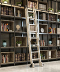 Heavy Duty Badass Round Tube Sliding Barn Door Hardware Track Kit Featuring Sleek Floor Roller Wheels on a library ladder.