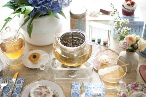 Kyoto 2-In-1 Tea Kettle And Tea Maker Glass Teapot with loose-leaf infuser on table setup with tea cups and floral decorations