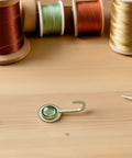 Pack Of 4 Self Adhesive Wall Hooks Featuring A Vintage Diamond Design on a wooden table with thread spools