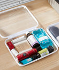 Hella Tough Four Piece Clear Hard Shell Case With Secure Zipper Closure, filled with toiletries and cosmetics, clear with white trim.