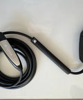 Tesla EV charging cable with black sheath and silver accent handle, coiled on white surface