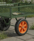 Heavy Duty Orange Solid Rubber Caster Wheel 7 Inch Non Pneumatic replacement on a green cart rolling on pavement.