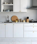 Rock Solid Zinc Alloy Cabinet Pulls Featuring A Slick Brushed Gold Finish 1 1/4 Inch Diameter Heavy Duty kitchen hardware on modern white kitchen cabinets.