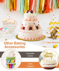 White and pink decorated cake with cherries, colorful cupcake liners, and cake toppers. 701 Piece Cake Decorating Kit With Baking Supplies