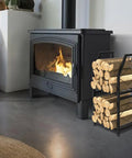 Two Tier Firewood Rack With 3 Hanging Hooks Heavy Duty Steel Wood Holder next to a lit indoor fireplace