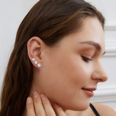 Snag These Fresh Flat Back Earrings Made From Light As Air Titanium Surgical Steel With Diamond Like Cubic Zirconia In Classic Round And Square Styles White Gold Plated Hypoallergenic Multiple Piercing Stud Set Truly Built For All Day Vibes worn by a model showing three square cubic zirconia studs.