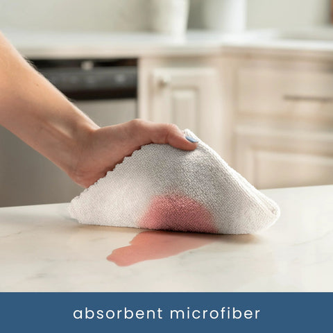 White microfiber cleaning cloth held in hand wiping a kitchen countertop; 11.8 x 11.8 inches