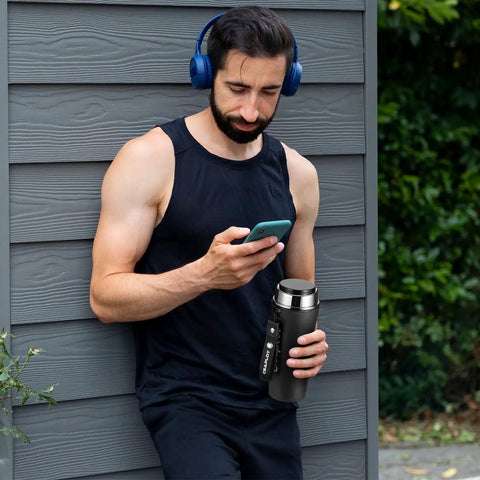 Man holding Global Travel Kettle With Dual Voltage 110-240V, portable electric design, LCD display visible, stainless steel finish.