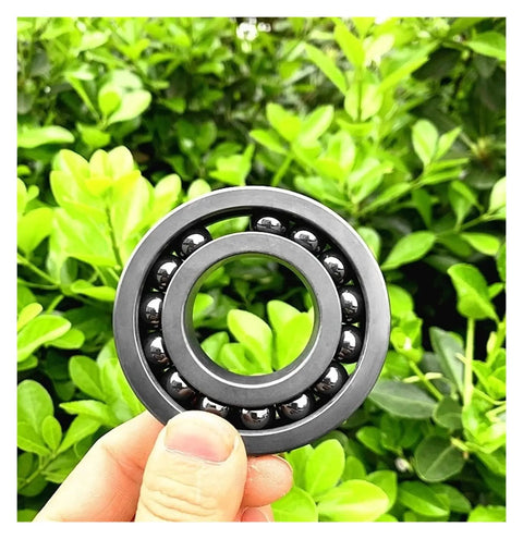 Top Tier Silicon Nitride Full Ceramic Ball Bearing 6210CEF Sized At 50X80X20mm shown against greenery.