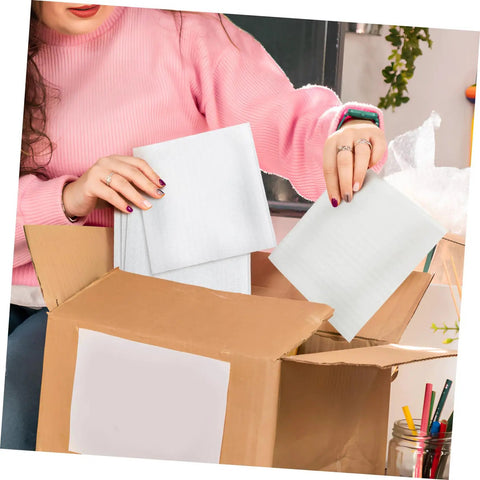 Person packing 100 Pack Epe Foam Pouches For Shipping Fragile Electronics into a cardboard box for safe delivery.